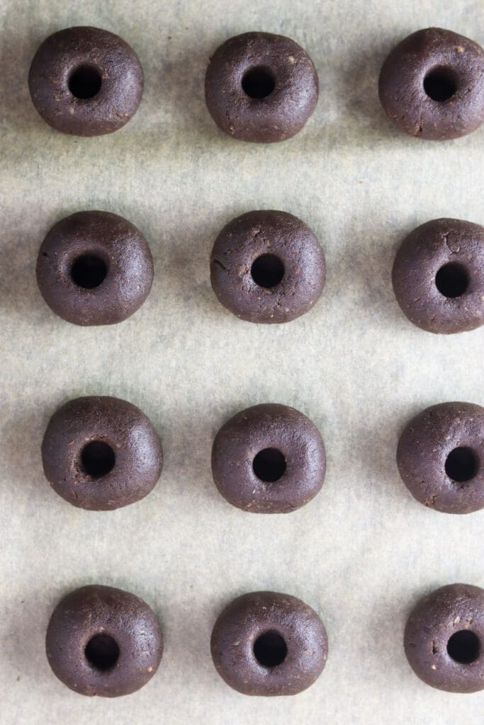 Cookie dough balls assembled, with cavities, ready to be baked.